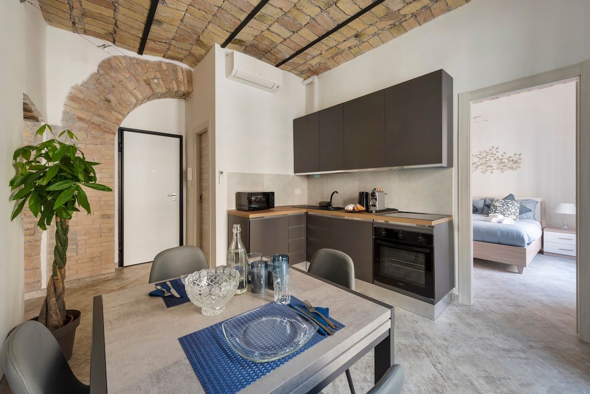 Dining table and kitchen under a brick barrel vault