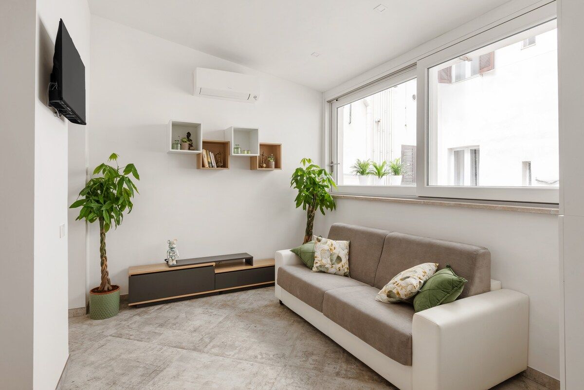 Living room with sofa, green cushions and a wide window