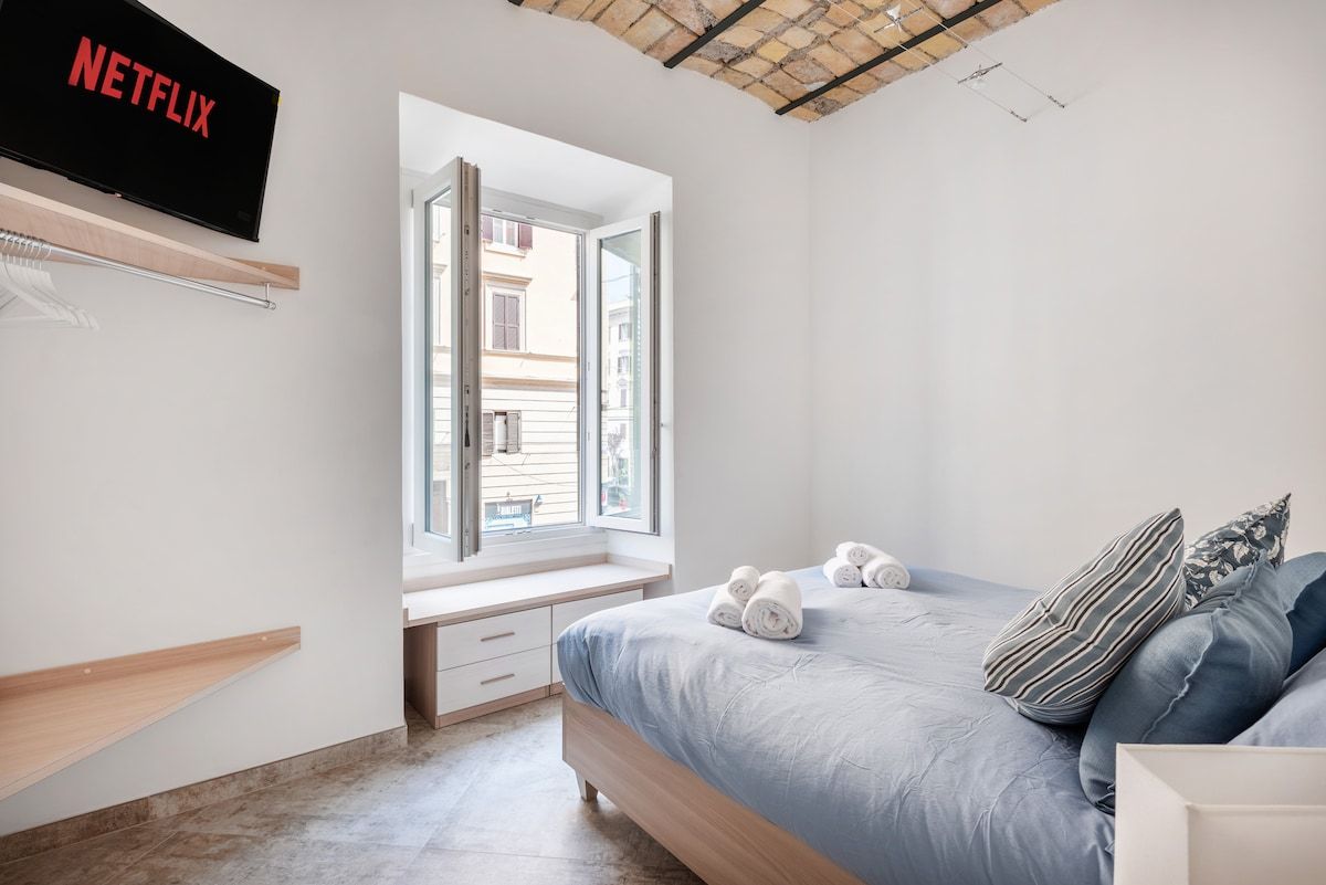 Double bedroom with blue linen and a tall window